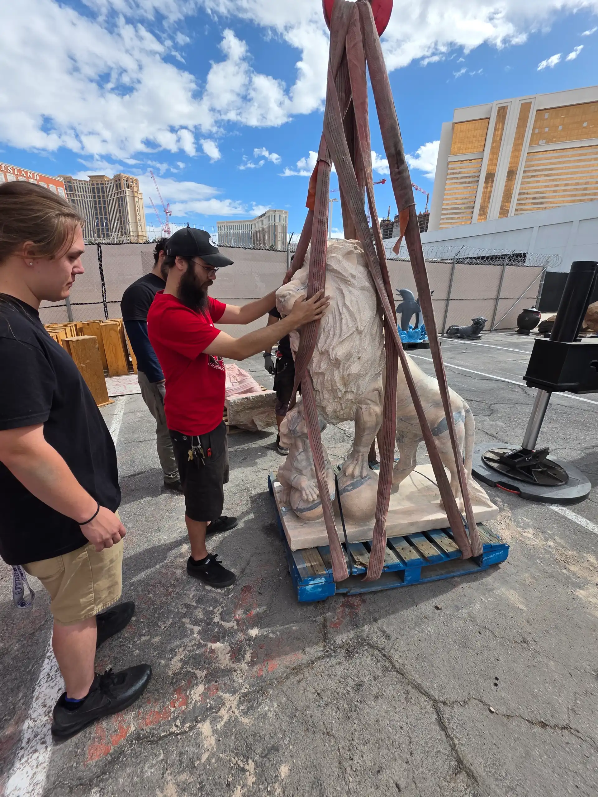 Crew rigging a marble lion sculpture for transport